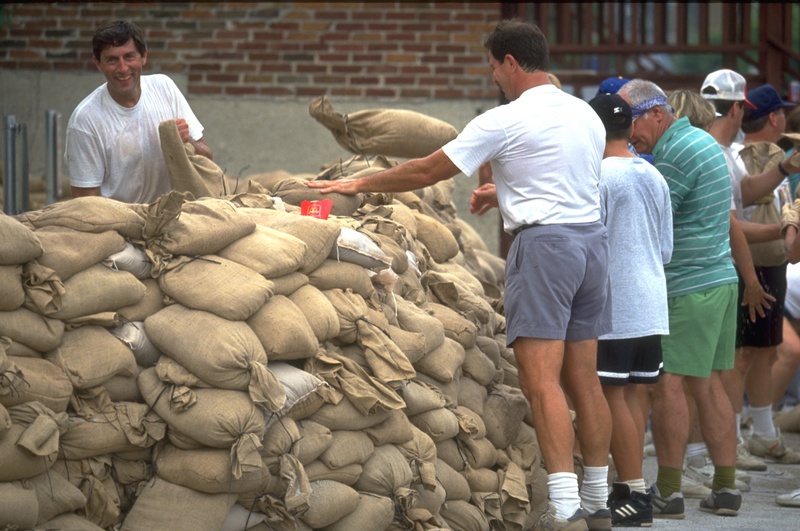 Residents and volunteers work to fill sandbags in an effort to stop the...