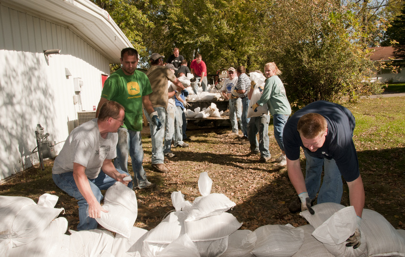 Volunteers remove sandbags from behind the local post office which were...