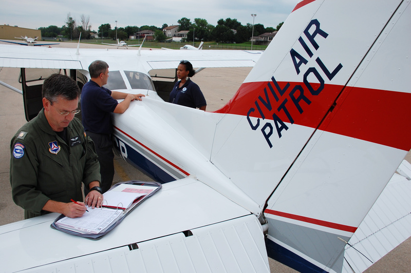 Civil Air Patrol pilot Tom Pflug checks his flight log as CAP photographer...