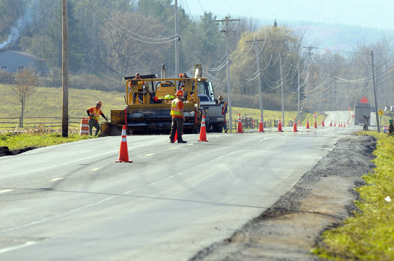 Repair crews replace a section of Route 30 after being damaged by flooding...