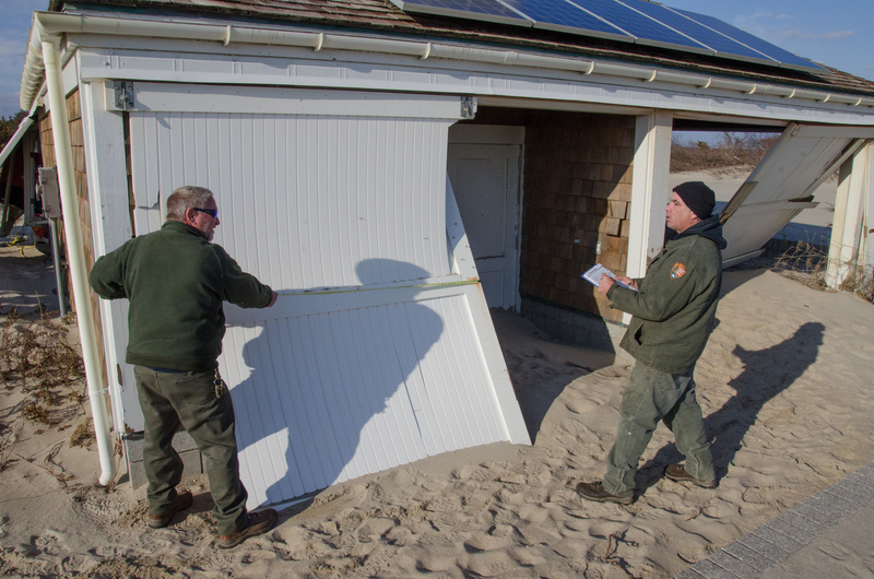 Two National Park Service employees measure a damaged door for replacement....