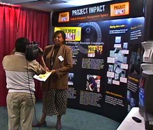 In front of the Project Impact display, WETV interviews the FEMA Project...